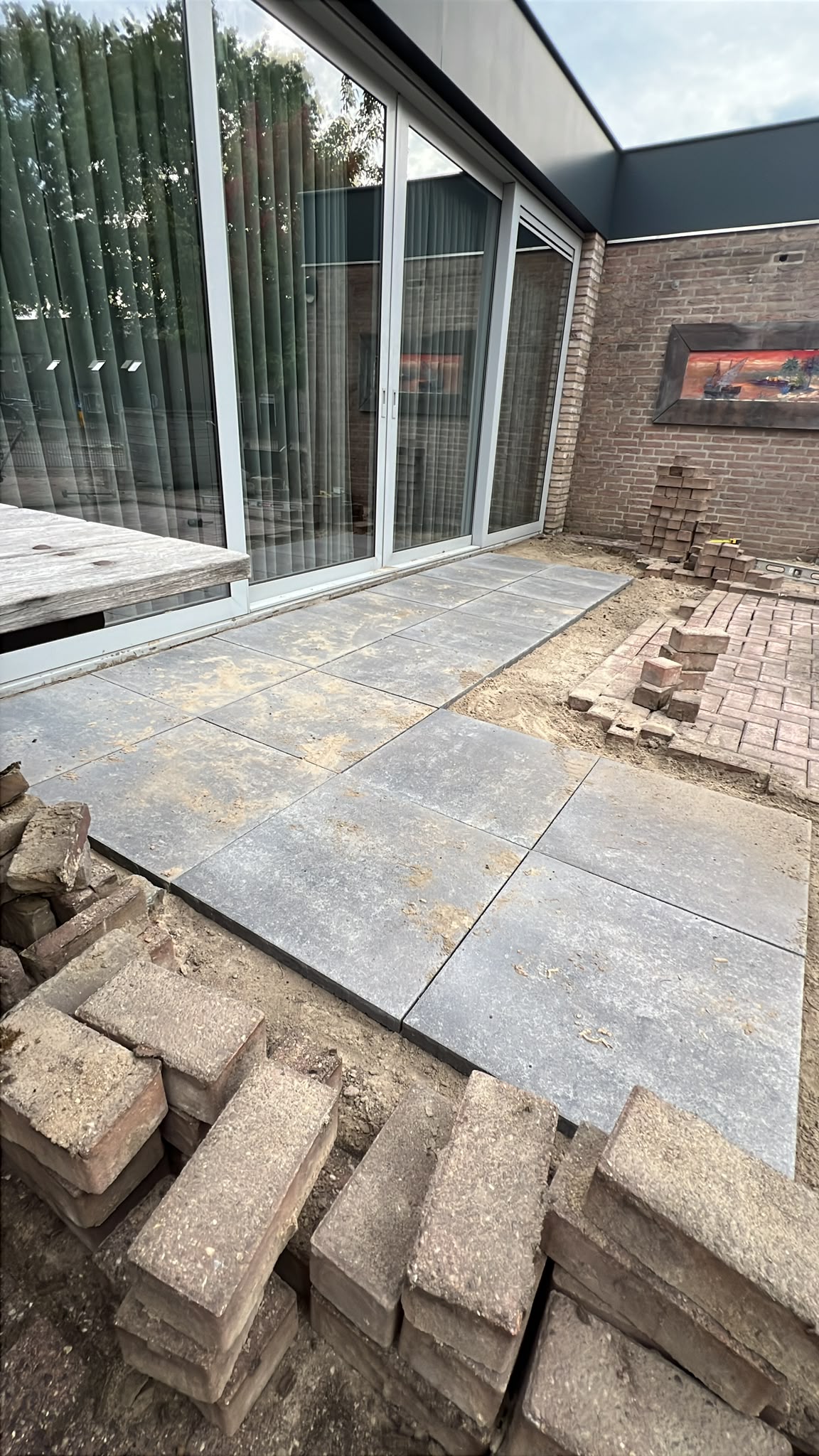 Natuursteen terrastegels in aanleg bij een moderne aanbouw