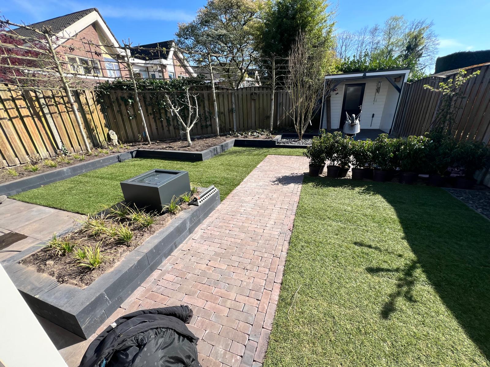 Detail van natuurstenen plantenbakken en klinkerpad
